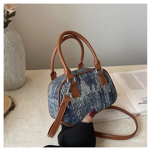 Detail of blue denim sequin cylinder bag with brown leather handles and silver hardware