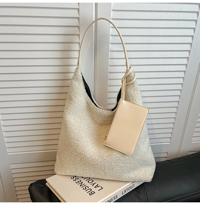 Detail of a creamy sherpa fleece tote bag with a matching small zipper pouch on a book
