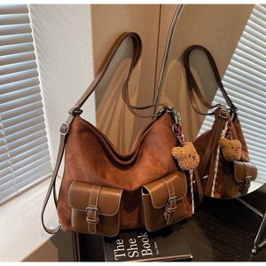 Detail of a brown suede Hobo bag with front pockets and elegant ribbon accessory