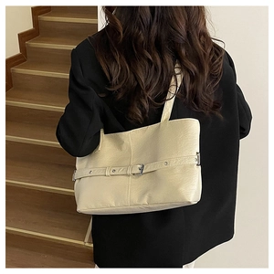 Dettaglio di una borsa tote retrò beige portata a spalla con finta pelle testurizzata fine
