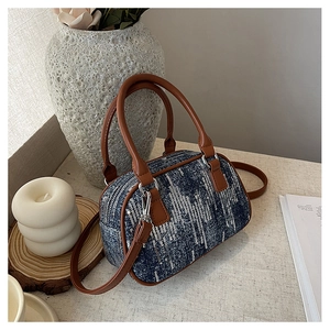 Detailed texture of blue denim canvas handbag with brown leather handles and silver hardware