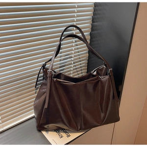 Macro shot of dark brown PU leather tote bag with soft folds and silver metal buckle