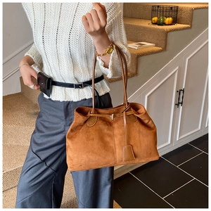 Détail d'un grand sac cabas vintage en daim marron avec bandoulière et pompon en cuir
