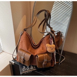 Detail view of brown suede tote bag featuring retro dual buckle pockets and plush bear charm