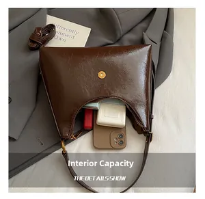Capacité interne du sac croissant marron contenant téléphone, rouge à lèvres et maquillage