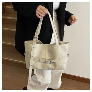 Dettaglio della borsa tote beige in finta pelle con cinturino decorativo in metallo