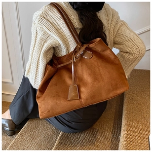 Vue détaillée du sac cabas en daim marron avec lanières en cuir sur pull d'automne chaud