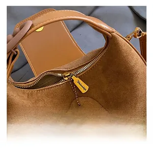 Detailed macro view of the brown suede crescent bag with a gold zipper and magnetic closure