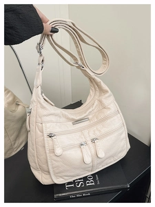 Detail of off-white soft PU leather hobo bag with multiple zippers and silver hardware