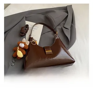 Détail du sac en cuir brillant marron foncé avec boucle en métal et breloque ours