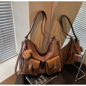 Detailed view of a brown suede hobo bag with front pockets and plush bear charm
