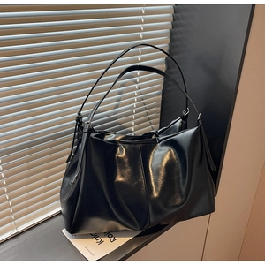 Detailed view of large black leather tote bag featuring adjustable metal buckle straps