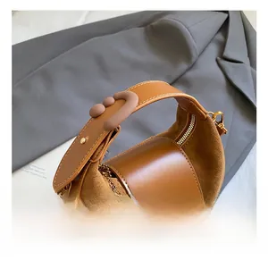 Close-up of retro brown hobo bag with suede stitching and unique round handle decor