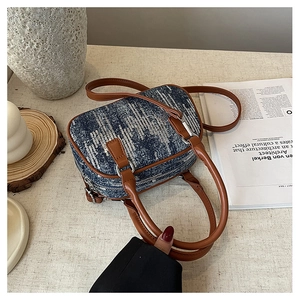 Detail of blue denim mini Boston bag featuring silver sequins and brown leather straps