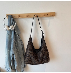 Leopard-Hobo-Tasche hängend mit einer Jeansjacke an einem hölzernen Wandhaken