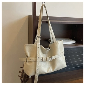 Dettaglio borsa tote retrò in ecopelle crema con cinghie su un supporto di legno