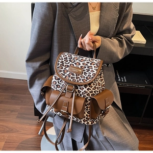 Sac à dos imprimé léopard avec détails en cuir marron tenu par un mannequin en bureau