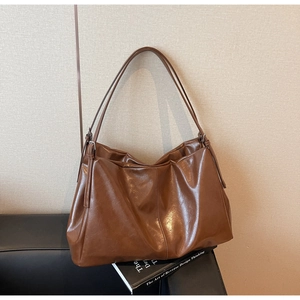 Close-up of caramel brown leather tote bag with glossy finish and metal buckle detail