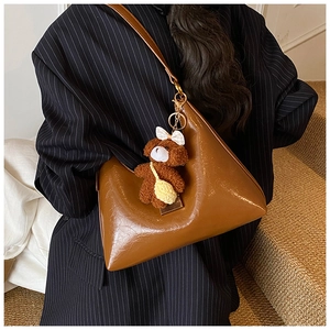 Sac hobo marron brillant avec pendentif ours porté sur un costume à rayures