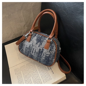 Detail of denim handbag with silver sequins and brown leather straps on vintage books