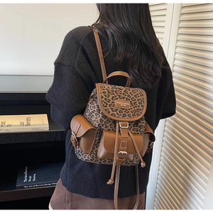 Détail du sac à dos léopard avec bordures en cuir marron et boucles métalliques