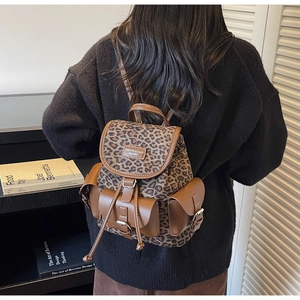 Détail du sac à dos léopard avec poches en cuir marron et fermeture à boucle en métal