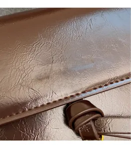 Gros plan détaillé du cuir marron foncé grainé avec logo doré et détail de nœud en cuir