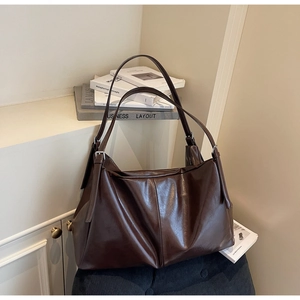 Detail view of large dark brown tote bag with adjustable strap and silver metal buckle
