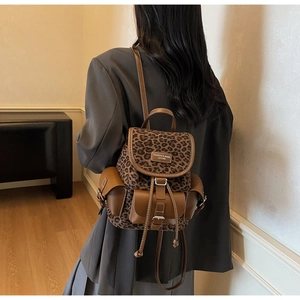 Vue détaillée du mini sac à dos à imprimé léopard avec finitions en cuir brun et boucles