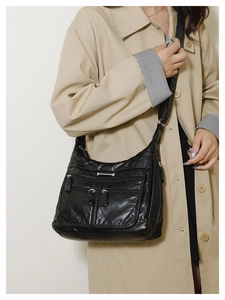 Detail of black faux leather crossbody bag with multiple zippers and pebble texture finish