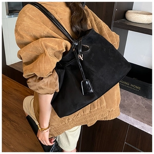 Détail du grand sac cabas en daim noir montrant sa texture mate et ses anses en cuir