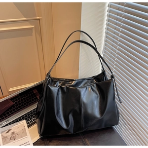 Detailed view of black pleated hobo bag with adjustable straps in a modern office setting