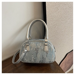 Detail of silver sequins on blue denim boston bag with metallic leather straps