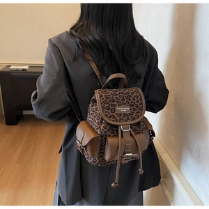 Détail du sac à dos imprimé léopard avec boucles magnétiques et attaches en cuir brun