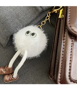 Gros plan d'un porte-clés poupée en peluche blanche avec de grands yeux et chaussures en cuir