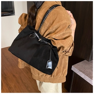 Détail du sac cabas en daim noir avec boucle dorée et bandoulière en cuir verni