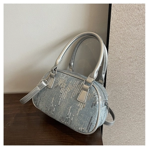Detailed view of silver sequins on blue denim texture and metallic handles of the bag