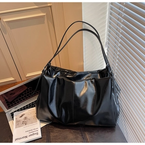 Detail of glossy black leather tote bag with pleated texture in an office lifestyle setting