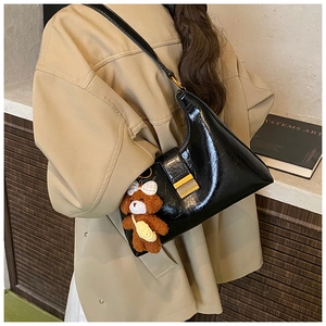 Détail du sac hobo noir brillant avec boucle dorée et pendentif ours en peluche marron