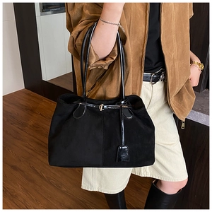 Détail du grand sac cabas en suède noir avec lanières en cuir et boucle sur le mannequin