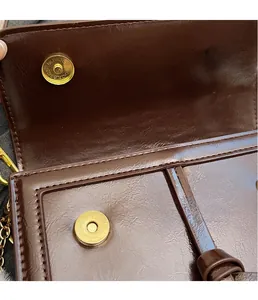 Détails des fermoirs magnétiques dorés et texture en cuir synthétique marron brillant
