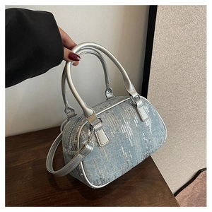 Detail of blue denim barrel bag with silver sequins and metallic top handles