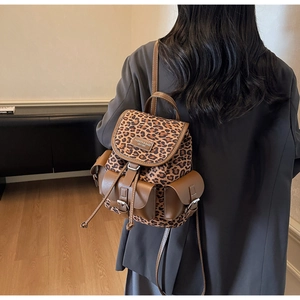 Gros plan du sac à dos léopard avec détails en cuir marron et plaque logo métallique