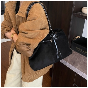 Détail du grand sac cabas en daim noir avec finitions en cuir verni et boucles dorées