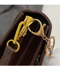 Gros plan sur les crochets dorés et les détails métalliques d'un sac en cuir marron