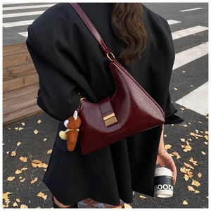 Détail du sac rétro bordeaux avec finition brillante et breloque ours en peluche