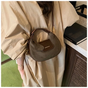 Detail of dark brown leather and suede half-moon hobo bag with gold metal buckle