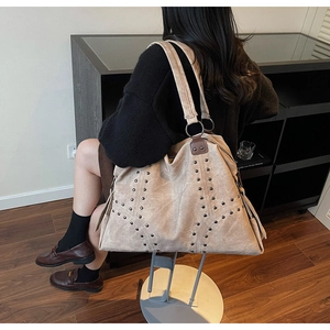 Détail d'un grand sac cabas beige avec rivets métalliques porté à l'épaule