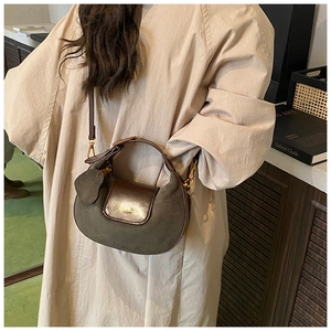 Detail of a retro dark green frosted suede half-moon bag with elegant gold hardware