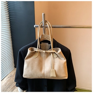 Gros plan sur un sac cabas en daim beige avec boucle suspendu sur un blazer